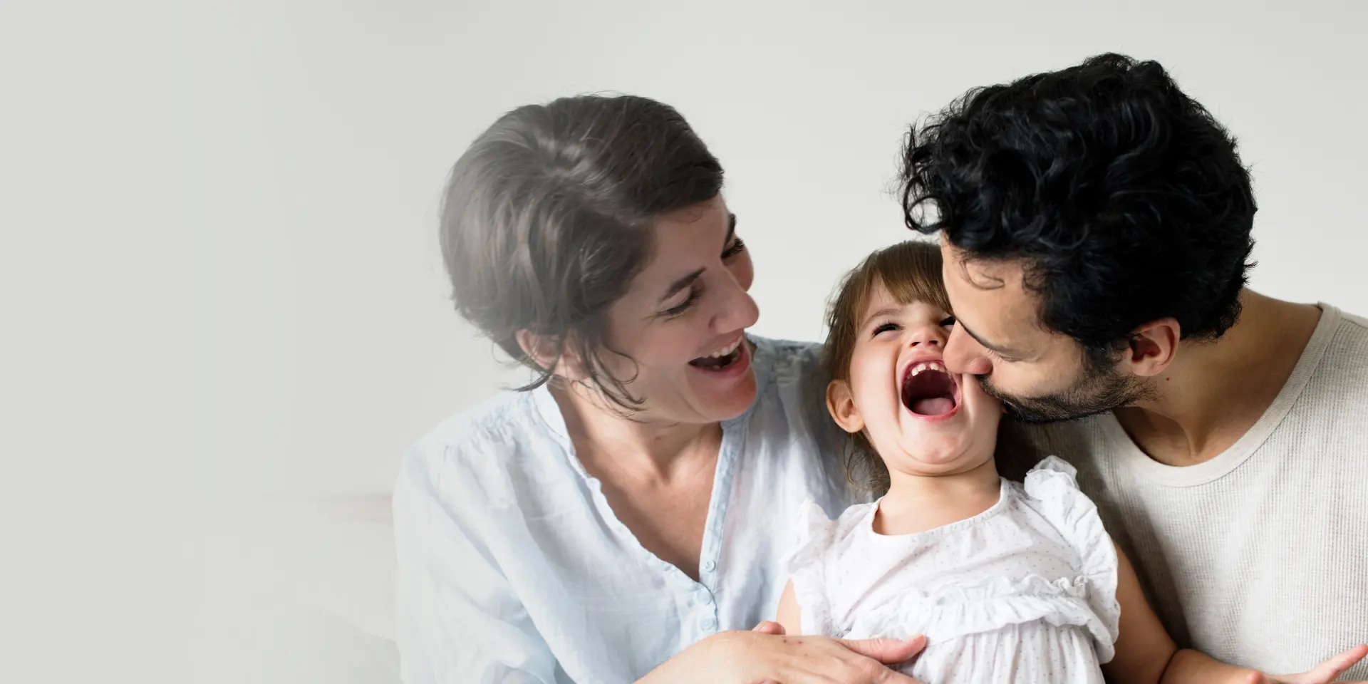 Parents laughing with their young daughter at home